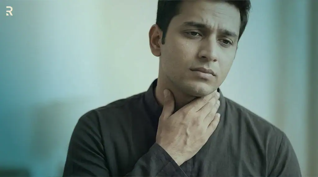 Worried Indian man touching the front of his neck where the thyroid gland sits